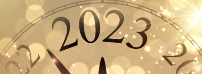 Neujahrsuhr zeigt 2023 mit goldenem Feuerwerk und Bokeh-Lichtern.
