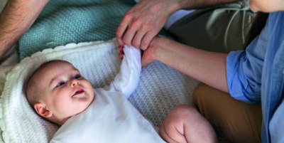 Baby, das mit Eltern Händchen hält.